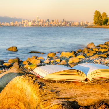This is a landscape, there are many rocks in the front and the ocean are at the back. This is sunset time and the buildings are far away .
